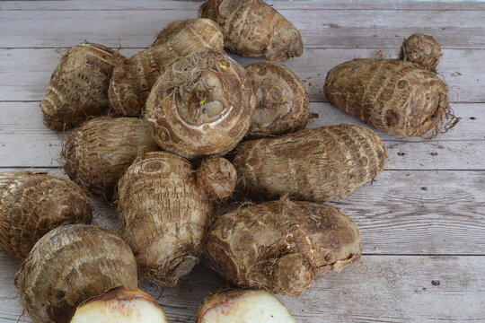 Heap of fresh raw taro root on wood
