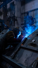 engineer welds metal on a freight car. sparks and smoke. welding. train and freight car manufacturing plant. metallurgical production, metal processing, heavy industry manufacturing process, factory