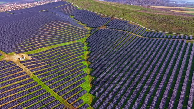 Rows upon rows of solar panels stretch over the rolling hills, gleaming under the bright midday sun. This green energy source fosters sustainability while enhancing the picturesque landscape.