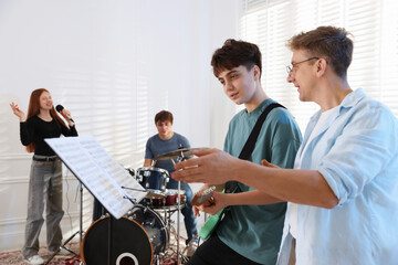 Teenage band practicing their performance with music teacher indoors © New Africa