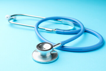Stethoscope on light blue background, closeup. Medical equipment