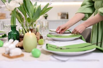 Woman setting festive table for Easter celebration at home, closeup