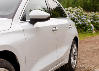 Low angle view of side back rear part of modern white new car. automobile perspective on countryside.