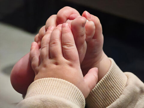 Eight month old baby holds his foot in his hands