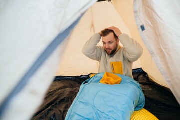 Man feeling frustrated inside camping tent © dsheremeta