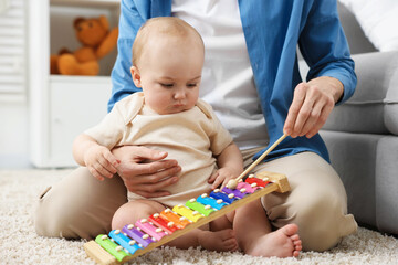 Mother playing with her cute baby on floor at home, closeup