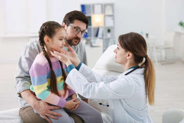 Little girl and her father having appointment with pediatrician in hospital. Doctor examining child