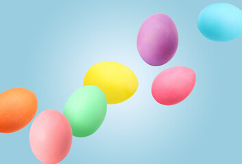 Easter eggs brightly dyed for holiday falling against blue background