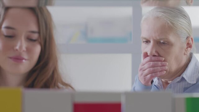 Female Pharmacist Recommending Cough Syrup to Senior Woman at Pharmacy Shelves