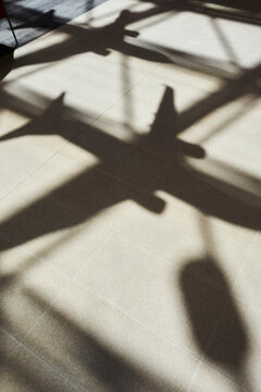 Natural sunlight casts dramatic plane shadows across white tiled floor creating abstract patterns
