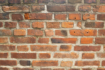 Textured red brick wall with various shades of brown and orange bricks, mortar joints visible, creating a rustic and industrial appearance suitable for backgrounds