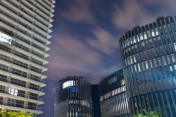 Fototapeta premium Modern urban skyline featuring tall residential and commercial buildings with glass facades against a twilight sky, showcasing architectural design and city life
