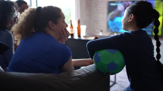 Friends eating pizza while watching football soccer on TV, the screen clearly visible during the match. Sports snacks, casual gathering, friendship, shared enjoyment, home viewing