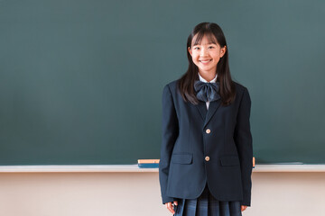 Female students in uniforms, elementary school, junior high school, and high school standing in front of the blackboard in the classroom © buritora