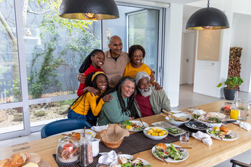 African American multi-generational family smiling at wooden table, sharing corn, pitchers, glasses