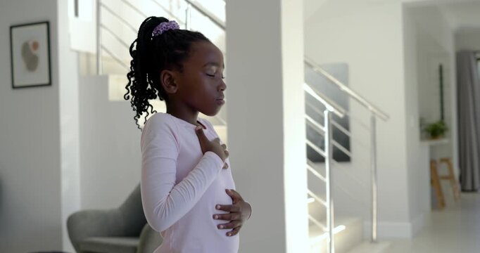 African schoolgirl placing hands, breathing slowly for calm by stairs wearing pink top