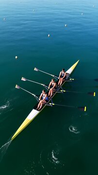 Aerial top view of a quad scull rowing team gliding on deep blue water, showcasing synchronization and athletic teamwork