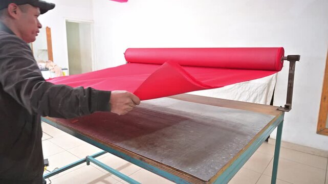 Tailor making precision side notches on red polyester fabric layers.