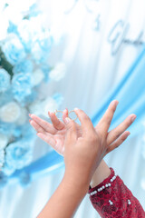 Elegant hands holding wedding rings with blue floral background