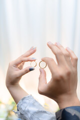 Woman's hands holding gold wedding rings in elegant gesture