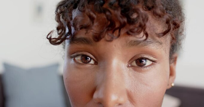 African American woman responding to camera gaze, blinking and showing stud earring on couch