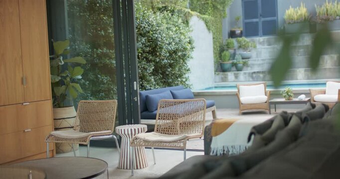 Camera is pulling back, revealing woven lounge chairs, blue sofa and plunge pool to show layout