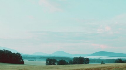 Tranquil landscape scene featuring rolling hills under a hazy blue sky