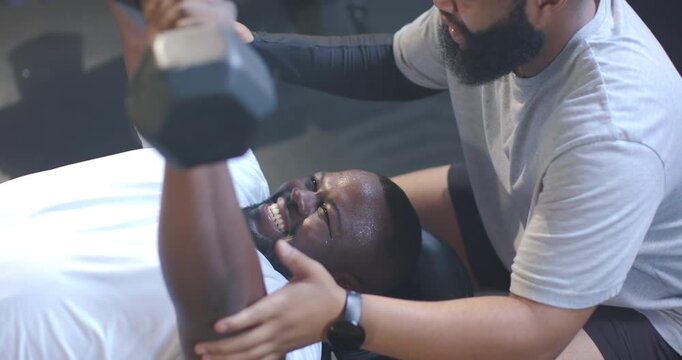 African American men trainer and client cueing and pressing weight on bench while spotting safely