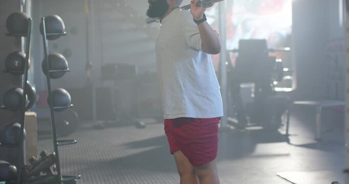 Man placing short barbell on back, doing squats at gym in red shorts for strength