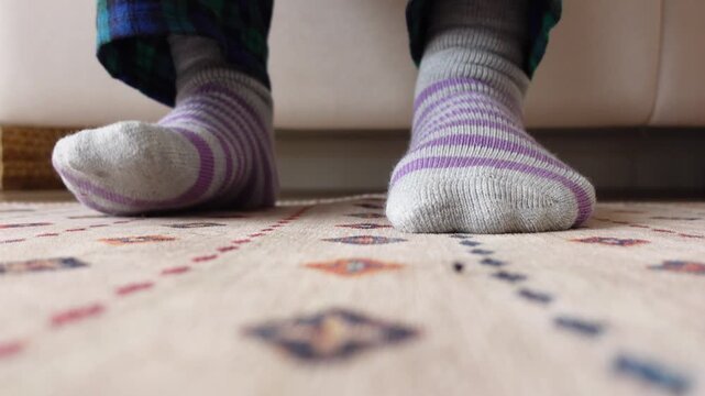 A close up shot of a person's feet in purple and gray striped socks tapping on a colorful patterned rug, dynamic footage of foot movement