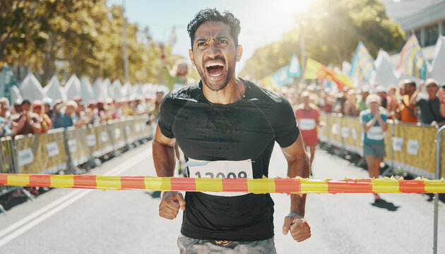 Excited male runner crossing the finish line at a marathon race.