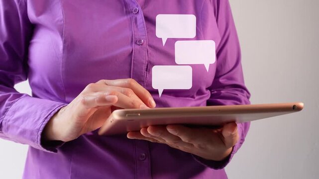 Close-up of a businesswoman interacting with her tablet and an animation of several speech bubbles, in a chat format.