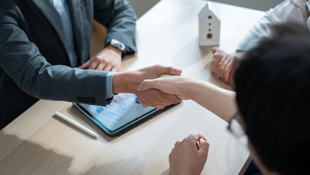 Close up of a real estate agent and client shaking hands for a successful home insurance deal or property mortgage. Concept of house buying, financial agreement, and investment security at office