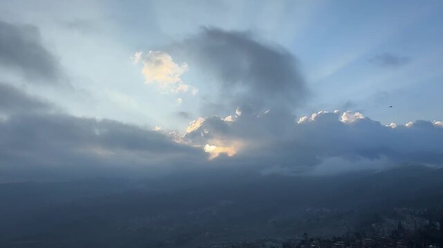 Cinematic time-lapse of crepuscular rays (Tyndall effect) shining through moving clouds over a mountain valley. Divine and peaceful atmosphere. 1080p.