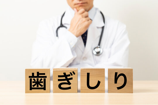 「歯ぎしり」と書かれたブロックと悩む医師