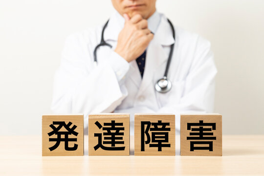 「発達障害」と書かれたブロックと悩む医師