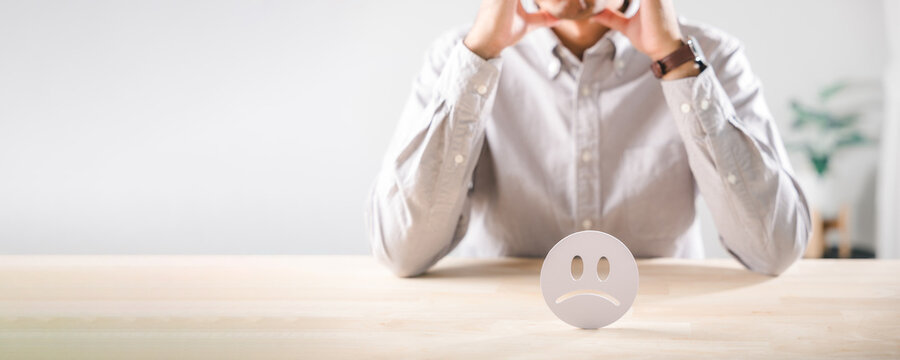 Customer shows unhappy feedback, reflecting low satisfaction, bad review icon sits on desk as person ponders complaint, considering poor service and overall experience