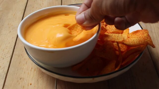 dipping tortilla chips into cheese sauce