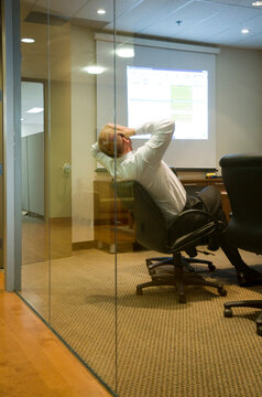 Canada, BC, Vancouver.  Businessman holding his head in glass office.