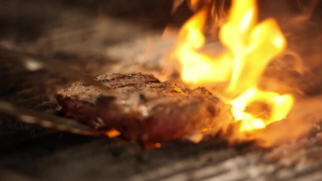 Juicy steak sizzling on a hot grill with flames and smoke