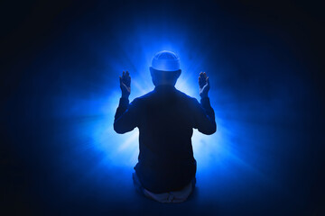 Back view silhouette of muslim man praying on dark blue background, eid adha mubarak concept