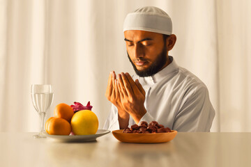 Young asian muslim man with beard praying at home, eid adha mubarak concept