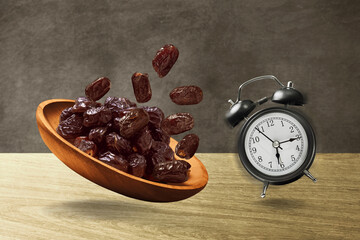 Dates fruits and alarm clock jumping on wooden table, eid adha mubarak concept