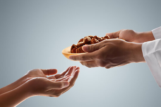 Hand of young muslim man giving dates fruit in wooden plate on white background, eid adha mubarak concept