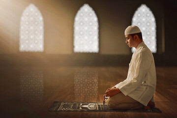 Portrait of young asian muslim man holding rosary beads in the mosque window arch,  eid adha mubarak concept