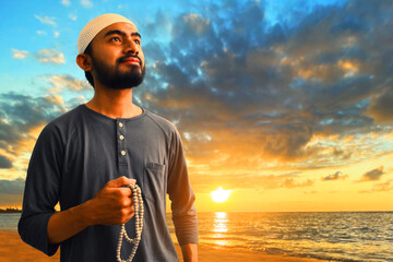 Portrait of young asian muslim man with beard enjoying beautiful sunset on sea beach holding rosary beads ,  eid adha mubarak concept