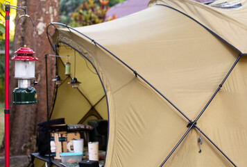 Cozy Camping Atmosphere with Vintage Lanterns and Tan Dome Tent in Lush Garden, Glamping Lifestyle and Outdoor Leisure Activity for Nature Travel and Summer Vacation Concept.