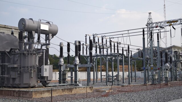 High voltage electrical power substation switchyard with large transformer and disconnect switch isolator equipment under sky for industrial energy distribution grid infrastructure.