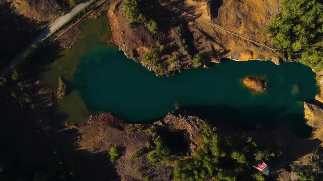 Birds eye drone shot rising above lake Orajarvi copper ore, sunny Salo, Finland