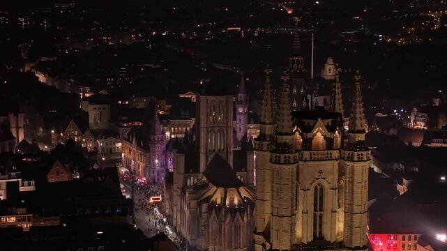 A sweeping drone shot revealing Ghent's nightscape, then showcasing the illuminated Belfry, followed by the St. Bavo's Cathedral, and finally St. Nicholas' Church in perfect alignment.